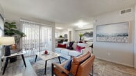This single-floor residence offers a thoughtfully designed open-concept layout that seamlessly connects the living, dining, and kitchen areas. The living room is a welcoming focal point, anchored by a brick fireplace and styled with light wood-look flooring, a marble-top coffee table, and a large sliding glass door that opens to a private balcony, filling the space with natural light. Adjacent to the living area, a dedicated dining nook provides an intimate setting with room for a small table, complemented by contemporary wall art. The kitchen is well-equipped with white shaker cabinetry, stainless steel appliances including a range, microwave, and dishwasher, light stone countertops, a subway tile backsplash, and a window that brings in additional natural light. The bedroom is a serene retreat featuring plush carpeting, a generous window with outdoor views, and a walk-in closet offering ample storage. A secondary room with carpet flooring and closet space serves well as a home office or additional sleeping area. The full bathroom is finished with light wood-look flooring, a combination tub and shower, and a vanity with stone countertops. Throughout, the neutral color palette and consistent finishes create a cohesive and comfortable living environment.