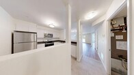 Located at 220 Ira Needles Blvd in Kitchener, Ontario, this well-appointed one-bedroom, one-bathroom unit offers a thoughtfully designed single-floor layout making efficient use of its space. The interior is finished with clean, neutral tones throughout, complemented by light wood-look laminate flooring in the living and bedroom areas and tile flooring in the kitchen, bathroom, and laundry room.

The combined kitchen and living room forms the heart of the unit. The kitchen is outfitted with crisp white cabinetry, a classic subway tile backsplash, dark countertops, and a full suite of stainless steel appliances including a refrigerator, electric range, and over-the-range microwave. Natural light filters into the living area through a window overlooking the greenery outside, creating a bright and welcoming atmosphere.

The generously sized primary bedroom features mirrored sliding closet doors and direct access to the rest of the unit, providing a comfortable and functional retreat. The full bathroom is finished in white with tile flooring and includes a soaker tub and shower combination. A dedicated in-unit laundry room with Whirlpool washer and dryer adds everyday convenience. The building exterior is set amid well-maintained landscaping with mature trees and manicured grounds.