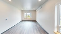 Located at 1120 S 11th St in Tacoma, WA, this thoughtfully designed two-bedroom, one-bathroom unit offers a clean and modern living environment on a single floor. The open layout connects a spacious living area to a well-appointed kitchen, which features light wood cabinetry, white countertops, a stainless steel sink, and white appliances including a range, dishwasher, and refrigerator. Recessed lighting illuminates the kitchen, adding a polished touch to its functional design. Consistent hardwood-style flooring flows throughout the unit, complemented by crisp white walls and natural wood door trim that lend a warm, contemporary aesthetic. A bright hallway connects the main living space to the two bedrooms, each offering natural light through windows with views of the surrounding Tacoma neighborhood. The primary bedroom is a comfortable size and includes a walk-in closet with wire shelving, providing practical storage. A wall-mounted heating unit is present in the main living and bedroom areas. The bathroom is cleanly finished with a tub/shower combination and stainless steel grab bars and towel bars. This unit presents a neat, move-in ready living space with a straightforward, modern design throughout.