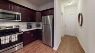 Located at 108 Moultrie Dr in Rincon, Georgia, this single-story home offers a thoughtfully designed layout with warm, cohesive finishes throughout. The kitchen is a standout feature, showcasing rich dark-stained shaker cabinets, granite countertops, a classic subway tile backsplash, and a full suite of stainless steel appliances including a refrigerator, range, and microwave. Wood-look flooring runs throughout the main living areas, lending warmth and continuity to the space. The living room centers around a custom-built white entertainment unit with barn-style sliding doors and open shelving, complemented by vaulted ceilings that enhance the sense of openness. A dedicated dining area provides an intimate space for meals. The primary bedroom features vaulted ceilings, a ceiling fan, and access to a walk-in closet. A secondary bedroom also offers vaulted ceilings and a walk-in closet with natural light from a window. The bathroom is finished with a granite-topped vanity, dark cabinetry, tile flooring, and a shower-tub combination with a window allowing in natural light. The attached garage includes an automatic opener and a separate utility room housing the water heater, offering practical storage and mechanical access.