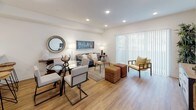 This single-floor residence offers a thoughtfully designed layout that balances open communal spaces with private retreats. The living and dining area forms the heart of the home, where warm wood-look flooring flows continuously throughout. Large sliding glass doors fitted with vertical blinds flood the living area with natural light while providing access to the outdoors. The open-plan design seamlessly connects the dining space—accommodating a glass-top table and seating—to the relaxed living area, creating an inviting environment for both entertaining and everyday living.

The kitchen is outfitted with rich dark cabinetry contrasted by crisp white quartz countertops, and features a full suite of stainless steel appliances including a refrigerator with ice maker, range, microwave, and dishwasher. The galley-style layout maximizes efficiency while maintaining a sleek, contemporary aesthetic.

The bedroom is a calm retreat, benefiting from a natural light source via a window and featuring mirrored sliding closet doors that enhance the sense of space. Recessed lighting and neutral walls contribute to the bright, airy atmosphere found throughout.

The bathroom is cleanly finished with dark wood-tone cabinetry, a white countertop vanity, and a full tub-shower combination, all grounded by the same warm wood-look flooring carried throughout the residence.