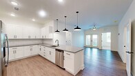 Located at 3530 Harbor Pointe Cir in Fruitland Park, FL, this single-story 2-bedroom, 2-bathroom home offers a clean, modern design with thoughtful finishes throughout. The open-concept living area seamlessly connects the kitchen, dining, and living spaces, all finished with durable wood-look flooring. The kitchen is a standout feature, boasting white shaker cabinetry, gray quartz countertops, a subway tile backsplash, stainless steel appliances, and a large central island with pendant lighting — ideal for both cooking and entertaining. French doors in the living area invite natural light and provide access to the patio. The spacious primary bedroom features plush carpet, a ceiling fan, and connects to a well-designed en-suite bathroom with a dual-sink vanity, gray countertops, and black hardware accents. The second bedroom is equally comfortable with soft carpet and a ceiling fan. The guest bathroom includes a single-sink vanity and a tub-shower combination. Additional highlights include four closets — one being a generous walk-in — a dedicated laundry room, pantry, and a hallway connecting the private quarters. The home's crisp white palette and consistent black hardware create a cohesive, contemporary aesthetic throughout.