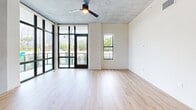 Located at 2281 N Lois Ave in Tampa, FL, this thoughtfully designed 3-bedroom, 3-bathroom residence offers a compelling blend of industrial and contemporary aesthetics across a single, well-organized floor. Exposed concrete ceilings provide a striking architectural contrast against warm hardwood-style flooring that flows throughout the entire space, creating a cohesive and modern atmosphere.

The open-concept kitchen and living area serves as the heart of the home, bathed in natural light from dramatic floor-to-ceiling windows and glass doors that open to a private balcony overlooking lush greenery and the surrounding Tampa skyline. The kitchen is outfitted with stainless steel appliances, including a French door refrigerator, wall oven, and dishwasher, complemented by sleek white cabinetry and a marble-style backsplash. A built-in wine cooler adds an elegant touch.

Each of the three bedrooms offers generous proportions, with the spacious primary bedroom featuring a walk-in closet with built-in wooden shelving. The three bathrooms are finished in a clean, minimalist style with illuminated mirrors, dark hardware accents, and soaking tubs. A dedicated laundry area includes an in-unit washer and a utility sink with white cabinetry, adding everyday convenience to this polished urban residence.