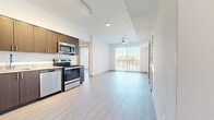 This well-appointed single-floor residence offers a thoughtfully designed open-concept layout that seamlessly connects the kitchen, dining, and living areas. Light-toned wood-look flooring runs throughout, lending a clean, cohesive aesthetic to the entire space.

The kitchen is a standout feature, outfitted with rich dark-wood cabinetry, granite countertops, a classic subway tile backsplash, and a full suite of stainless steel appliances including a range, microwave, dishwasher, and refrigerator. Track lighting above enhances both functionality and style.

The open living area extends toward a private balcony accessed through sliding glass doors with vertical blinds, allowing abundant natural light to fill the space. A ceiling fan adds comfort to the main living zone. Louvered closet doors provide storage near the entry area, adding a practical architectural detail.

The bedrooms are bright and tranquil, each featuring wood-look flooring and windows fitted with horizontal blinds that offer privacy while maintaining natural light. The bathroom is finished with large-format tile flooring and includes a soaking tub with tiled surround and a dark wood vanity, maintaining a consistent modern aesthetic.

Overall, the space presents a clean, contemporary design with quality finishes, making it a functional and visually cohesive residence.