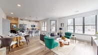 This well-designed single-floor residence offers a thoughtful layout centered around an open-concept living, dining, and kitchen area that encourages a seamless flow between spaces. Light hardwood-style flooring runs throughout, complementing the crisp white walls and creating a bright, cohesive aesthetic.

The kitchen is outfitted with stainless steel appliances, granite countertops, dark lower cabinetry, and white upper cabinets accented by a subway tile backsplash. Pendant lighting illuminates a breakfast bar with seating, while a nearby window allows natural light to fill the space. The adjoining dining area accommodates a round table with mixed seating, set beneath wall-mounted artwork.

The living area is generously sized, featuring multiple windows that bring in abundant natural light and exterior views. A separate den or sitting room provides a quieter retreat, styled with a tufted sofa and floating display shelves.

The primary bedroom is bright and spacious, with windows on multiple walls, direct access to an en-suite bathroom, and a walk-in closet. The en-suite includes a dual-sink vanity with dark cabinetry, a glass-enclosed shower, and hardwood-style flooring. A secondary bedroom offers similar finishes, supported by a well-appointed half bath with a dark-framed vanity and white countertop.
