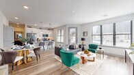 This well-designed single-floor residence offers a thoughtful layout centered around an open-concept living, dining, and kitchen area that encourages a seamless flow between spaces. Light hardwood-style flooring runs throughout, complementing the crisp white walls and creating a bright, cohesive aesthetic.

The kitchen is outfitted with stainless steel appliances, granite countertops, dark lower cabinetry, and white upper cabinets accented by a subway tile backsplash. Pendant lighting illuminates a breakfast bar with seating, while a nearby window allows natural light to fill the space. The adjoining dining area accommodates a round table with mixed seating, set beneath wall-mounted artwork.

The living area is generously sized, featuring multiple windows that bring in abundant natural light and exterior views. A separate den or sitting room provides a quieter retreat, styled with a tufted sofa and floating display shelves.

The primary bedroom is bright and spacious, with windows on multiple walls, direct access to an en-suite bathroom, and a walk-in closet. The en-suite includes a dual-sink vanity with dark cabinetry, a glass-enclosed shower, and hardwood-style flooring. A secondary bedroom offers similar finishes, supported by a well-appointed half bath with a dark-framed vanity and white countertop.