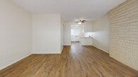 This two-floor residence offers a thoughtfully designed layout with distinct living spaces across both levels. The main living area is a standout, anchored by a floor-to-ceiling light brick fireplace wall that serves as a dramatic focal point. Sliding glass doors invite natural light and provide outdoor access, while hardwood-style flooring runs throughout the common areas, adding warmth and continuity.

The kitchen is well-equipped, featuring white cabinetry with brushed nickel hardware, light stone countertops, and a striking mosaic tile backsplash in warm earth tones. White appliances include an electric range with over-the-range microwave and a dishwasher. A large window above the sink fills the kitchen with natural light. A peninsula counter connects the kitchen to a secondary dining or living space, which features a ceiling fan and an open, airy feel.

The bathroom includes a tub-shower combination with sliding glass doors, mosaic tile flooring, built-in shelving, and a wide vanity with ample counter space and mirror. A second bathroom features a clean white vanity with a large mirror.

Bedrooms are carpeted and include ceiling fans and windows with outdoor views, contributing to a comfortable, well-lit atmosphere throughout the home.