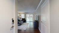 This thoughtfully designed single-floor residence offers a functional and stylish layout across six distinct spaces. The entry hallway opens directly into a bright, generously sized living room finished with rich dark hardwood flooring and crown molding. A large sliding glass door floods the space with natural light while offering views of mature trees and lush outdoor greenery, complemented by an additional side window for cross-ventilation and ambiance.

The adjacent dining area continues the hardwood flooring and features a large window overlooking the outdoors, creating an inviting setting for everyday meals. The kitchen is well-equipped with white shaker cabinetry, granite countertops, a decorative tile backsplash, and a full suite of stainless steel appliances, including a refrigerator, range, and microwave.

The spacious bedroom is carpeted for comfort and includes a ceiling fan, a window for natural light, and direct access to the bathroom. The bathroom is finished with dark hardwood flooring, white vanity cabinetry, granite countertops, pendant lighting, and a large mirror, offering a clean and modern aesthetic. A dedicated closet completes the private quarters, providing practical storage solutions throughout this well-balanced home.