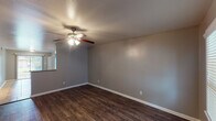 Located in College Station, TX, this two-bedroom, one-bathroom unit offers a well-organized single-floor layout designed for comfortable everyday living. Rich, dark hardwood-style flooring flows throughout the living areas and both bedrooms, providing a warm and cohesive aesthetic against the neutral gray walls and crisp white trim.

The living area is generously proportioned, featuring a ceiling fan with integrated lighting and a textured ceiling. Natural light filters in through windows, creating a bright and welcoming atmosphere. Both bedrooms continue the dark flooring and are each equipped with ceiling fans. One bedroom includes a window overlooking the outdoors, while the other features a built-in closet with bifold doors, offering practical storage solutions.

The kitchen is well-appointed with white cabinetry, light marble-style countertops, and a suite of black appliances including a refrigerator, range, and dishwasher. Track lighting illuminates the space, and light ceramic tile flooring adds a clean contrast. An adjacent closet provides additional storage or laundry hookup space.

The bathroom is functional and neatly finished, featuring a marble-style vanity countertop, a window with blinds for natural ventilation, and a tub-shower combination. The unit's straightforward layout and durable finishes make it a practical and comfortable residence.