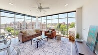 Located at 302 Vine St in West Lafayette, Indiana, this 3-bedroom, 2-bathroom unit offers a well-designed single-floor layout that balances comfort and modern style. The living room is an immediate standout, showcasing dramatic floor-to-ceiling windows that flood the space with natural light and provide sweeping views of the surrounding cityscape and greenery. A ceiling fan adds a practical touch to this bright, open gathering area.

The kitchen flows seamlessly from the living space and features rich cherry wood cabinetry, granite-style countertops, black appliances including a refrigerator, electric range, and built-in microwave, along with a generous breakfast bar with seating — ideal for casual dining and entertaining.

The primary bedroom is a comfortable retreat with carpeted flooring, a ceiling fan, and sliding glass doors that open to a private balcony with city views. Each bedroom offers access to closet space, with some rooms featuring walk-in closets with wire shelving systems.

The two bathrooms are finished with wood-toned cabinetry, light countertops, and wood-look flooring. The full bathroom includes a shower/tub combination, while the second bathroom serves as a convenient half or guest bath. Clean white walls and consistent finishes throughout give the entire space a cohesive, well-maintained appearance.