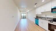Located on Weddington Street in Los Angeles, CA, this thoughtfully designed one-bedroom, one-bathroom unit offers a clean, modern aesthetic throughout its single-floor layout. Light-toned hardwood flooring runs seamlessly through every room, creating a warm and cohesive foundation that complements the crisp white walls.

The open kitchen and living area form the heart of the unit. The kitchen is outfitted with white shaker-style cabinetry, gray countertops, and a full suite of stainless steel appliances, including a gas range, built-in microwave, refrigerator, and dishwasher. The adjoining living area is bright and airy, featuring recessed lighting and a sliding glass door that opens to a private balcony with views of surrounding greenery.

The bedroom is a comfortable, well-proportioned space bathed in natural light from a large black-framed window that frames outdoor treetop views. Clean white walls and continued wood flooring give the room a serene, uncluttered feel.

The bathroom is efficiently appointed with white cabinetry, a dark countertop vanity with an undermount sink, a large mirror, built-in wall shelving, and a full tub and shower combination enclosed by sliding glass doors. The unit's consistent use of light tones and modern finishes gives the entire space a fresh, move-in-ready character.