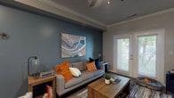 This thoughtfully designed single-floor residence combines contemporary style with comfortable, functional living. The open-concept main living area is anchored by rich hardwood-style flooring, crown molding, and a ceiling fan overhead. A striking teal accent wall adds a bold focal point to the living room, complemented by French doors that invite natural light and provide outdoor access. The space flows seamlessly into a dedicated dining area with bar seating, creating an ideal setting for both everyday living and entertaining.

The kitchen is outfitted with stainless steel appliances, including a full-size refrigerator and range, crisp white cabinetry, and hardwood-style flooring that carries throughout the common areas. A conveniently positioned closet provides additional storage just off the kitchen.

The primary bedroom features a soft carpet underfoot, a prominent teal accent wall, a ceiling fan, and a large window that fills the room with natural light. A second bedroom mirrors this comfortable layout, also carpeted and well-lit, with ample space for storage. The bathroom includes a full soaking tub and shower combination with clean white tile surround, offering a serene retreat. Throughout the residence, a cohesive warm-neutral and teal color palette creates a welcoming, modern ambiance.