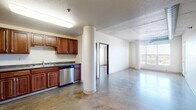 Located at 1919 University Dr N in Fargo, ND, this 2-bedroom, 2-bathroom residence showcases a distinctive industrial-modern aesthetic throughout. Polished concrete floors run continuously across the entire space, complementing exposed ductwork and structural concrete columns that lend an urban loft character to the open layout.

The kitchen is well-appointed with rich wood cabinetry, stainless steel appliances including a dishwasher, microwave, and gas range, and a double-basin sink — all anchored around a bold structural column that adds architectural interest. The open living area flows naturally from the kitchen, receiving generous natural light through large windows and offering access to a private balcony with outdoor views.

Both bedrooms are spacious and bright, each featuring windows that bring in natural light. The primary bedroom is generously sized, while the second bedroom also offers comfortable proportions. Three closets throughout the unit provide ample storage. The two bathrooms are finished with warm wood vanities, grey countertops, and well-lit mirrors. One bathroom features a full soaking tub and shower combination. An in-unit laundry area adds everyday convenience. The overall ambiance is clean, open, and urban, with a cohesive industrial palette throughout.