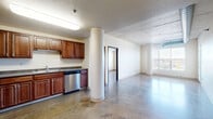 Located at 1919 University Dr N in Fargo, ND, this 2-bedroom, 2-bathroom residence showcases a distinctive industrial-modern aesthetic throughout. Polished concrete floors run continuously across the entire space, complementing exposed ductwork and structural concrete columns that lend an urban loft character to the open layout.

The kitchen is well-appointed with rich wood cabinetry, stainless steel appliances including a dishwasher, microwave, and gas range, and a double-basin sink — all anchored around a bold structural column that adds architectural interest. The open living area flows naturally from the kitchen, receiving generous natural light through large windows and offering access to a private balcony with outdoor views.

Both bedrooms are spacious and bright, each featuring windows that bring in natural light. The primary bedroom is generously sized, while the second bedroom also offers comfortable proportions. Three closets throughout the unit provide ample storage. The two bathrooms are finished with warm wood vanities, grey countertops, and well-lit mirrors. One bathroom features a full soaking tub and shower combination. An in-unit laundry area adds everyday convenience. The overall ambiance is clean, open, and urban, with a cohesive industrial palette throughout.
