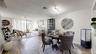 This two-story home offers a thoughtfully designed layout that balances open communal spaces with comfortable private retreats. The main floor features a bright, open-concept living and dining area united by warm wood-look flooring. The living room is anchored by large floor-to-ceiling windows that invite abundant natural light and offer pleasant outdoor views, creating an airy, welcoming atmosphere. The dining area flows seamlessly from the living space and connects directly to the kitchen via a convenient pass-through window. The kitchen is well-equipped with stainless steel appliances, white cabinetry, granite countertops, and a classic tile backsplash, combining functionality with a clean, modern aesthetic. A staircase with white balustrade leads to the upper level, where the bedrooms are located. Each bedroom features plush carpeting, vaulted ceilings, and generous natural light. The primary bedroom includes an en-suite bathroom, while additional bedrooms are spacious and well-proportioned. The bathrooms are finished with neutral tile and tub-shower combinations. Throughout the home, a cohesive neutral color palette with soft grey and white tones lends a calm, contemporary feel to every room.