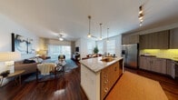This single-floor residence offers a thoughtfully designed open-concept layout that seamlessly connects the kitchen, dining, and living areas. The kitchen is a standout feature, equipped with stainless steel appliances including a French door refrigerator, electric range, and over-the-range microwave. A large central island with granite countertops and an undermount sink serves as the focal point, complemented by modern wood-tone cabinetry, subway tile backsplash, and pendant lighting overhead. Rich hardwood flooring flows throughout the main living areas, adding warmth and continuity to the space. The living room is bright and welcoming, with a ceiling fan, floor-to-ceiling sliding glass doors that invite natural light, and access to an outdoor area. The dining space adjacent to the kitchen benefits from large windows that further enhance the airy atmosphere. The bedroom is generously sized, featuring plush carpeting, multiple windows with blinds and curtain accents, and a ceiling fan. The bathroom is well-appointed with a full soaking tub, tile surround, granite vanity, and modern cabinetry, with hardwood flooring extending into the hallway. Throughout the residence, clean white walls and consistent finishes create a cohesive, contemporary aesthetic.