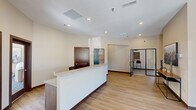 The Sheppard Hills Commons Clubhouse in Rapid City, South Dakota, is a thoughtfully designed single-floor community facility that provides residents with a well-rounded gathering space. Upon entry, a welcoming foyer greets visitors with light wood flooring, curated artwork, and a console table accented by local South Dakota-inspired pieces, setting a warm and modern tone throughout.

The reception area features a clean, white front desk, wood-look flooring, and recessed lighting, creating a polished and functional front-of-house experience. Adjacent to this is a spacious lounge and game room outfitted with plush carpeting, multiple seating arrangements, a wall-mounted TV, a full-size pool table, and a foosball table — all illuminated by abundant natural light from large windows overlooking the surrounding neighborhood.

A dedicated golf simulator room offers an immersive experience complete with a professional-grade hitting mat and projection screen setup. A smaller dining nook with a round table and large window provides a bright, casual space for conversation or small gatherings.

Two well-appointed restrooms feature wood-look flooring, marble-top vanities, and playful artwork. Throughout the clubhouse, a neutral warm palette, recessed lighting, and consistent modern finishes create a cohesive, inviting atmosphere ideal for community connection and recreation.