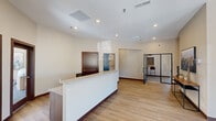 The Sheppard Hills Commons Clubhouse in Rapid City, South Dakota, is a thoughtfully designed single-floor community facility that provides residents with a well-rounded gathering space. Upon entry, a welcoming foyer greets visitors with light wood flooring, curated artwork, and a console table accented by local South Dakota-inspired pieces, setting a warm and modern tone throughout.

The reception area features a clean, white front desk, wood-look flooring, and recessed lighting, creating a polished and functional front-of-house experience. Adjacent to this is a spacious lounge and game room outfitted with plush carpeting, multiple seating arrangements, a wall-mounted TV, a full-size pool table, and a foosball table — all illuminated by abundant natural light from large windows overlooking the surrounding neighborhood.

A dedicated golf simulator room offers an immersive experience complete with a professional-grade hitting mat and projection screen setup. A smaller dining nook with a round table and large window provides a bright, casual space for conversation or small gatherings.

Two well-appointed restrooms feature wood-look flooring, marble-top vanities, and playful artwork. Throughout the clubhouse, a neutral warm palette, recessed lighting, and consistent modern finishes create a cohesive, inviting atmosphere ideal for community connection and recreation.