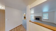 Located at 9902 Cranberry Ln NW in Silverdale, Washington, this single-floor residence offers a well-organized layout designed for comfortable everyday living. The spacious living room serves as the heart of the home, centered around a striking brick fireplace and flanked by windows that invite natural light. Plush carpet flows throughout the living and bedroom areas, while hardwood-style flooring runs through the kitchen and entry zones, creating a clear and practical distinction between spaces. The kitchen is well-appointed with warm honey-toned wood cabinetry extending to the ceiling for ample storage, granite-style countertops, and stainless steel appliances including a refrigerator and electric range. A pass-through counter connects the kitchen to the living area, enhancing the open feel of the space. Multiple bedrooms offer a quiet retreat, each carpeted and equipped with baseboard heating and window blinds for privacy and comfort. The bathroom features a full tub-and-shower combination with brushed nickel fixtures and a vanity with light countertops. A dedicated in-unit laundry area with a full-size washer and dryer adds everyday convenience. Overall, the residence presents a clean, functional, and inviting environment suited for a variety of lifestyles.