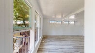 Located at 390 N Madison Ave in Pasadena, California, this 2-bedroom, 1-bathroom unit offers a thoughtfully updated single-floor layout. Light wood-look flooring runs throughout the space, lending a clean, cohesive aesthetic to every room.

The spacious primary bedroom is the largest room in the unit, featuring mirrored sliding closet doors and direct access to the bathroom. The second bedroom includes a wall-mounted air conditioning unit and high horizontal windows that allow in natural light while maintaining privacy.

The kitchen is well-appointed with white shaker-style cabinetry, open upper shelving, granite-look countertops, a stainless steel sink, and stainless steel appliances including a refrigerator and range. A window above the counter adds natural light to the workspace.

The bathroom is finished with classic black-and-white mosaic tile flooring, a white vanity with a granite-look countertop, and a tub-shower combo with a window above for ventilation and natural light.

The main living area is bright and open, with a large bank of windows and a glass door that opens to an outdoor balcony area, framing views of surrounding greenery. Textured ceilings and crisp white walls complement the light flooring throughout, creating a clean and welcoming atmosphere.