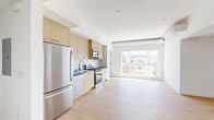 Located at 611 N Virgil Avenue in Los Angeles, this thoughtfully designed residence offers three bedrooms and three bathrooms across a single floor. The open-concept living and kitchen area serves as the heart of the home, where light wood-tone cabinetry, dark stone countertops, a white subway tile backsplash, and a full suite of stainless steel appliances — including a gas range, dishwasher, microwave, and refrigerator — create a clean, contemporary aesthetic. Light hardwood flooring flows seamlessly throughout the living spaces and bedrooms, enhancing the bright, airy feel. Large picture windows in the living area and bedrooms flood the interior with natural light while framing views of the surrounding Los Angeles neighborhood. The bedrooms are well-proportioned, featuring crisp white walls, light wood floors, and generous closet space. Each of the three bathrooms is appointed with striking floor-to-ceiling green subway tile in the walk-in glass showers, terrazzo tile flooring, and warm wood vanities accented by matte black hardware — a cohesive and stylish design touch. Exposed ductwork and architectural ceiling details in the living area add an industrial-modern character to the overall aesthetic, making this a well-appointed home in a vibrant Los Angeles location.