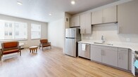 This thoughtfully laid-out 2-bedroom, 1-bathroom residence in Millcreek, Utah offers a clean, modern aesthetic throughout its single floor. Light wood-tone flooring flows seamlessly across every room, creating a bright and cohesive feel. The open kitchen is well-appointed with taupe cabinetry, white countertops, and a full suite of stainless steel appliances including a refrigerator, dishwasher, microwave, and range — ideal for everyday cooking and entertaining. The living area benefits from natural light provided by multiple windows, lending an airy, welcoming atmosphere to the space. Both bedrooms are comfortably sized, each featuring sliding-door closets and neutral wall tones that offer flexibility for a variety of furnishing styles. The primary bedroom provides a generous footprint with room for a full bedroom suite. The full bathroom is finished with a wide vanity, white countertop, and a tub-shower combination. A dedicated laundry room houses a full-size washer and dryer, adding considerable everyday convenience. Two closets provide ample storage throughout the unit. The overall design is clean and contemporary, with recessed lighting, textured ceilings, and a neutral palette that makes this residence move-in ready.
