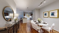 Harbor Cove presents a thoughtfully designed 1-bedroom, 1-bathroom residence that maximizes every square foot through an efficient, open-concept floor plan. Rich hardwood-style flooring flows throughout the main living areas, creating a warm and cohesive aesthetic. The living room is a standout space, featuring a tray ceiling, a ceiling fan, and large French doors with transom windows that invite abundant natural light and views of the outdoors. The dining area sits adjacent to the kitchen and is illuminated by modern track lighting, offering a seamless transition between spaces. The kitchen features a breakfast bar with counter seating, stainless steel appliances including a refrigerator and range, and ample cabinetry with warm wood tones. The bedroom is a comfortable retreat, complete with plush carpeting, a ceiling fan, a large window, and access to a walk-in closet outfitted with wire shelving and hanging rods. The bathroom is appointed with rich wood cabinetry, granite countertops, and hardwood-style flooring. A dedicated in-unit laundry room with full-size washer and dryer hookups and built-in shelving adds significant everyday convenience. The overall ambiance is modern, clean, and inviting throughout.