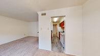 Located at 3920 Bell St in Amarillo, Texas, this single-floor unit offers a practical and comfortable layout with well-defined living spaces throughout. The living area is finished with plush carpet and crown molding, lending a clean, classic aesthetic. A wide arched opening connects the living space to the galley-style kitchen, which features warm wood cabinetry, dark granite-style countertops, a white electric range, a stainless steel sink, and durable wood-look flooring. A chandelier visible through the kitchen pass-through adds a decorative touch to the adjoining dining area. The bedroom is generously sized, outfitted with carpet, a ceiling fan with light fixture, and a window with blinds that allows for natural light. A second carpeted room with crown molding and a large window provides additional flexible living space. The bathroom includes a vanity with a granite-style countertop and a red cabinet base, a full tub-shower combination, and wood-look flooring. Throughout the unit, neutral wall tones, consistent flooring transitions, and functional design elements create a cohesive and move-in-ready environment.