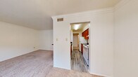 Located at 3920 Bell St in Amarillo, Texas, this single-floor unit offers a practical and comfortable layout with well-defined living spaces throughout. The living area is finished with plush carpet and crown molding, lending a clean, classic aesthetic. A wide arched opening connects the living space to the galley-style kitchen, which features warm wood cabinetry, dark granite-style countertops, a white electric range, a stainless steel sink, and durable wood-look flooring. A chandelier visible through the kitchen pass-through adds a decorative touch to the adjoining dining area. The bedroom is generously sized, outfitted with carpet, a ceiling fan with light fixture, and a window with blinds that allows for natural light. A second carpeted room with crown molding and a large window provides additional flexible living space. The bathroom includes a vanity with a granite-style countertop and a red cabinet base, a full tub-shower combination, and wood-look flooring. Throughout the unit, neutral wall tones, consistent flooring transitions, and functional design elements create a cohesive and move-in-ready environment.