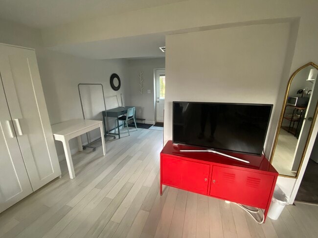 View of the TV and TV stand in the basement unit. - 7922 Fitzroy St