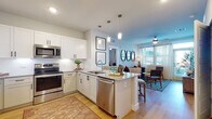 This single-floor residence is thoughtfully designed with a bright, open-concept layout that seamlessly connects the kitchen, dining, and living areas. The kitchen is outfitted with white shaker-style cabinetry, granite countertops, a full suite of stainless steel appliances, and a central island with a undermount sink, all set above light wood-tone flooring that extends throughout the main living spaces. Pendant lighting above the island and recessed ceiling lights provide layered illumination.

The living area benefits from multiple windows fitted with plantation shutters, allowing generous natural light to fill the space. A ceiling fan adds comfort, while the open connection to the kitchen and dining area creates an inviting, cohesive flow.

Two bedrooms are finished with plush carpeting and plantation-shuttered windows. Each offers a calm, well-proportioned retreat with ample wall space for artwork or furnishings.

The two bathrooms mirror the home's refined aesthetic, featuring granite-topped vanities with white shaker cabinetry, undermount sinks, large framed mirrors, and tile shower surrounds. One bathroom includes a dual-sink vanity, providing added functionality. Light wood-tone flooring carries through both bathrooms, maintaining a consistent, polished look across the entire residence.