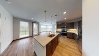 This well-designed single-floor residence offers a thoughtfully laid-out open-concept living space centered around a fully equipped kitchen. The kitchen is a standout feature, showcasing rich dark-stained cabinetry, light quartz countertops, a tile backsplash, and a full suite of stainless steel appliances including a range, microwave, and refrigerator. A central island with an undermount sink and pendant lighting above serves as both a functional workspace and a natural gathering point, flowing seamlessly into the adjacent living area. Warm hardwood-style flooring runs throughout the main living spaces, adding continuity and warmth to the open layout. A sliding glass door leads to a private balcony, inviting natural light into the living area.

The bedrooms are carpeted for comfort and feature large windows with blinds that frame outdoor views, filling each room with abundant natural light. Generous closet space is provided in the bedrooms, with built-in shelving and hanging rods for organized storage.

The bathrooms are finished with earthy stone-look tile flooring and dark wood vanity cabinetry topped with light countertops. A full tub and shower combination is present, along with well-lit vanity mirrors. Additional closet space adjacent to the bathroom further enhances the home's practical storage solutions.