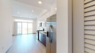 Located in the heart of Los Angeles, this modern single-floor unit at 1265 Stearns Dr offers a thoughtfully designed living space with clean lines and contemporary finishes. The open-concept layout seamlessly connects the kitchen and living area, creating a bright and functional environment.

The kitchen is a standout feature, equipped with a full suite of stainless steel appliances including a gas range, built-in microwave, dishwasher, and a side-by-side refrigerator with an in-door water and ice dispenser. A crisp white subway tile backsplash complements the white upper cabinetry, while rich dark wood lower cabinets add warmth and contrast. Light quartz countertops and a deep stainless steel sink complete the polished look.

The living area is generously proportioned and bathed in natural light, thanks to large sliding glass doors that open to a private balcony with outdoor views. A transom window above the doors further amplifies the brightness of the space. Light wood-tone flooring flows continuously throughout, lending a cohesive and airy feel.

The bathroom is cleanly appointed with full-height tile surround in the soaking tub and shower combination, a dark wood vanity with a white countertop, and a backlit mirror. Recessed lighting throughout the unit ensures consistent, modern illumination in every room.
