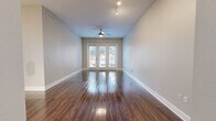 This thoughtfully designed 2-bedroom, 1-bathroom residence offers a functional and attractive single-floor layout. The open-concept living, dining, and kitchen area serves as the heart of the home, featuring rich dark hardwood flooring that extends throughout the main living spaces. A ceiling fan and track lighting complement the room, while a set of French doors floods the area with natural light and provides outdoor access.

The kitchen is a standout feature, showcasing white shaker-style cabinetry, a decorative tile backsplash, stainless steel appliances, and a central island with a white quartz countertop and pendant lighting above — ideal for both meal preparation and casual dining. A pantry provides additional storage convenience.

Both bedrooms are carpeted for comfort and include ceiling fans and ample natural light from large windows. Multiple closets, including a walk-in, offer generous storage. The bathroom is well-equipped with a white vanity with quartz countertops, a framed mirror, a tiled soaking tub, and direct access to a walk-in closet with built-in shelving. A dedicated laundry room and hallway with additional closets round out this efficiently organized home.