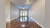 This thoughtfully designed 2-bedroom, 1-bathroom residence offers a functional and attractive single-floor layout. The open-concept living, dining, and kitchen area serves as the heart of the home, featuring rich dark hardwood flooring that extends throughout the main living spaces. A ceiling fan and track lighting complement the room, while a set of French doors floods the area with natural light and provides outdoor access.

The kitchen is a standout feature, showcasing white shaker-style cabinetry, a decorative tile backsplash, stainless steel appliances, and a central island with a white quartz countertop and pendant lighting above — ideal for both meal preparation and casual dining. A pantry provides additional storage convenience.

Both bedrooms are carpeted for comfort and include ceiling fans and ample natural light from large windows. Multiple closets, including a walk-in, offer generous storage. The bathroom is well-equipped with a white vanity with quartz countertops, a framed mirror, a tiled soaking tub, and direct access to a walk-in closet with built-in shelving. A dedicated laundry room and hallway with additional closets round out this efficiently organized home.