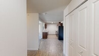 Located in Post Falls, Idaho, this 2-bedroom, 2-bathroom residence offers a practical and well-organized single-floor layout designed for comfortable everyday living. The open-concept kitchen and living area serves as the heart of the home, where the kitchen features rich dark-wood cabinetry, light countertops, black appliances including a range, microwave, and refrigerator, and durable wood-look flooring that extends into the wet areas. Ample upper and lower cabinet storage provides generous workspace for cooking and entertaining. The living room is a bright, open space with plush carpeting, a wall-mounted air conditioning unit, and a sliding glass door fitted with vertical blinds that allows an abundance of natural light and outdoor views. Both bedrooms are carpeted and well-lit, with the primary bedroom featuring a ceiling fan and a window with scenic views of the surrounding Idaho landscape. The second bedroom also benefits from natural light through a large window. Each bathroom offers clean, functional finishes — one includes a shower stall with wood-look flooring and vanity cabinetry, while the other features a full bathtub and shower combination. Two hallways connect the spaces efficiently, contributing to a cohesive and easy-to-navigate floor plan throughout the unit.