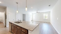 Located at 452 Moss Trail in Goodlettsville, Tennessee, this well-appointed 2-bedroom, 2-bathroom single-story home offers a thoughtfully designed layout with modern finishes throughout. The open-concept kitchen and living area serves as the heart of the home, where rich dark-brown cabinetry reaches toward the ceiling, providing generous storage. A large central island with granite countertops and pendant lighting anchors the space, complemented by a tile backsplash and a full suite of stainless steel appliances. Light hardwood-style flooring flows across the main living areas, while ceiling fans keep the space comfortable and bright. Multiple windows allow natural light to fill the living room, offering views of the surrounding greenery. The spacious primary bedroom features plush carpeting, a ceiling fan, and access to a walk-in closet. The secondary bedroom is equally comfortable, with soft carpet and natural light from a window with blinds. A hallway with additional built-in cabinetry and granite surfaces connects the bedrooms to the rest of the home. Three closets, two full bathrooms, and a dedicated utility room round out the practical and functional floor plan, making this home both comfortable and efficient.