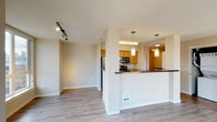 Located at 1211 Dexter Avenue North in Seattle's South Lake Union neighborhood, this single-floor residence offers a well-designed layout with thoughtful finishes throughout. The open-concept living and kitchen area serves as the heart of the home, where warm honey-toned cabinetry, dark countertops, and stainless steel appliances—including a refrigerator, microwave, and dishwasher—come together in a functional galley-style kitchen. Pendant lighting above the breakfast bar adds warmth, while track lighting in the living area provides flexible illumination. Light wood-style flooring flows through the main living spaces, complementing the neutral color palette. The bedrooms are carpeted and generously sized, each featuring large windows that frame views of the surrounding Seattle cityscape, along with ceiling fans for comfort and baseboard heating. Two full bathrooms are appointed with warm wood vanities, dark countertops, and tub-shower combinations, maintaining a consistent and cohesive aesthetic. A stacked in-unit washer and dryer adds everyday convenience. Natural light fills the space through oversized windows, connecting the interior to the vibrant urban surroundings of one of Seattle's most dynamic and walkable neighborhoods.