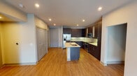 Located at 1025 Preston Rd in Plano, TX, this thoughtfully designed single-floor residence showcases a contemporary aesthetic throughout. The open-concept kitchen serves as the heart of the space, featuring rich dark-espresso cabinetry, stainless steel appliances including a French door refrigerator, electric range, and built-in microwave. A light quartz-topped center island with an undermount sink provides both additional prep space and a natural gathering point. Subtle green tile backsplash adds a refined touch against the warm wood-look flooring that flows throughout the main living areas. The expansive living area offers a clean, open layout with recessed lighting and neutral walls, providing a versatile canvas. A set of double doors adds architectural interest near the entryway. The bedrooms are finished with plush wall-to-wall carpeting and feature ceiling fans, natural light from windows with roller shades, and a comfortable, quiet atmosphere. The bathrooms are elegantly appointed with large-format light tile flooring, dark wood vanities, white quartz countertops, and glass-enclosed showers. Each bathroom connects to a dedicated walk-in closet with built-in shelving and hanging rods, offering generous storage. The overall ambiance is modern, clean, and move-in ready.