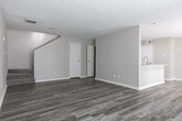 This two-story residence in Houston, TX (77090) presents a clean, modern aesthetic with consistent wood-look flooring and neutral gray tones carried throughout both levels. The main floor opens into a spacious living area with a textured ceiling, wide baseboards, and a front entry door flanked by windows that invite natural light. Adjacent to the living space, the kitchen is well-appointed with white shaker cabinetry, light quartz countertops, a subway tile backsplash, stainless steel appliances including a refrigerator, range, microwave, and dishwasher, and a deep undermount sink. A peninsula provides additional counter space and casual seating potential. A dedicated laundry area with a full-size washer and dryer is conveniently located nearby.

Upstairs, the layout includes multiple bedrooms, one of which features vaulted ceilings, French doors that bring in generous natural light, and dual closets offering ample storage. Additional bedrooms include closet space and share the same warm flooring. The bathrooms are finished with white vanities, quartz countertops, brushed nickel fixtures, and wood-look flooring, with one bathroom featuring a tub-shower combination.