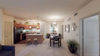 The Summit's two-bedroom, two-bathroom residence is thoughtfully designed across a single floor, offering a functional and cohesive open-concept layout. The kitchen serves as a central highlight, featuring warm wood cabinetry extending to the upper walls, black appliances including a range and refrigerator, hardwood-style flooring, and a generous island with a light countertop and bar seating. Pendant lighting illuminates both the island and the adjacent dining area, where crown molding adds a refined architectural detail throughout the shared living space.

The living room is carpeted and receives natural light through large sliding glass doors fitted with vertical blinds, contributing to an airy, comfortable atmosphere. Crown molding continues in this space, maintaining a consistent design character.

Both bedrooms are carpeted and include ceiling fans. The primary bedroom features a walk-in closet and ample space for furnishings. The two bathrooms are finished with wood-style flooring, white cabinetry, and tiled tub-shower combinations with decorative tile accents. The overall palette of warm neutrals and wood tones creates a welcoming, cohesive environment throughout the residence.