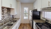 This fully renovated unit at 444 E 4th Street, #324 in Escondido offers a thoughtfully updated interior across a single level. Throughout the living areas and bedrooms, warm-toned wood-look flooring creates a cohesive and inviting atmosphere, complemented by freshly painted white walls and textured ceilings that add subtle depth to each room.

The living area is bright and open, featuring a ceiling fan with light fixture and a large sliding glass door fitted with vertical blinds that usher in generous natural light. An additional window further enhances the airy feel of the space.

The kitchen has been tastefully renovated with crisp white shaker-style cabinetry, stone-look countertops, a mosaic tile backsplash, and black appliances including an electric range and refrigerator. A window above the counter brings in natural light, making the galley-style layout both functional and pleasant.

The bedrooms are well-proportioned, each featuring wood-look flooring, windows with blinds, and clean white walls that offer a neutral backdrop. The bathroom includes a full tub-shower combination with chrome fixtures, a vanity with stone-look countertop, and wood-look flooring that ties into the rest of the unit. In-unit laundry is conveniently accessible, adding to the overall practicality of this renovated Escondido residence.