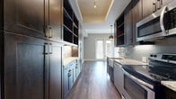 This 420 square foot apartment in Dallas, TX, showcases efficient design and contemporary aesthetics. The open-concept layout combines the kitchen and living area, maximizing the use of space. The kitchen features dark wood cabinetry, granite countertops, and stainless steel appliances, creating a sleek and functional cooking space. Wood-look flooring extends throughout, lending warmth and continuity.

The living area is brightened by a set of French doors with built-in blinds, offering natural light and potential outdoor access. The bathroom impresses with a modern design, including a tiled shower, glass enclosure, and a dark wood vanity with a granite countertop. Storage solutions are integrated throughout, with ample cabinet space in the kitchen and bathroom.

The apartment's neutral color palette, combining soft grays and whites, creates a calming atmosphere and provides a blank canvas for personalization. Recessed lighting and pendant fixtures add to the contemporary feel. Despite its compact size, the thoughtful layout and high-end finishes make this space feel both stylish and comfortable.