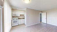 Located in El Paso, TX, this single-story unit offers a practical and efficiently arranged floor plan across a compact footprint. The layout includes a living area, kitchen, one bathroom, and multiple rooms, all unified by light-toned luxury vinyl plank flooring that runs throughout the space.

The living area is bright and open, featuring neutral beige walls, a textured ceiling, and a wall-mounted air conditioning unit beside a front entry door. The adjoining kitchen is well-equipped with white cabinetry, granite-style countertops, a built-in microwave, electric range, full-size refrigerator, and a single-basin sink — providing all essential cooking amenities in a clean, functional layout.

The bedrooms are simply designed with the same light flooring and neutral walls, offering a clean canvas for personalization. The spacious primary bedroom features a window with vertical blinds that allows natural light in, along with its own wall A/C unit. Additional rooms maintain a similarly understated aesthetic.

The bathroom is outfitted with a white vanity cabinet, a framed mirror with overhead lighting, and light wood-tone flooring, creating a clean and bright atmosphere. Throughout the unit, white baseboards and panel-style doors contribute to a consistent, tidy appearance. This unit is a straightforward, move-in-ready space suited for practical everyday living.