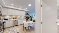 This thoughtfully designed 1-bedroom, 1-bathroom unit offers an efficient and functional layout across a single floor. The open-concept kitchen and living area serves as the heart of the home, where the kitchen features flat-panel white cabinetry extending to the ceiling, a light grey tile backsplash, white quartz countertops, stainless steel appliances including a dishwasher and refrigerator, and ample under-cabinet lighting. A round dining table with modern white chairs sits at the center of the combined space, ideal for everyday dining. The living area is bright and airy, with light hardwood flooring throughout and large floor-to-ceiling patio doors that open to a private balcony, filling the space with natural light and outdoor views. The bedroom is a calm, well-proportioned retreat featuring a large window with exterior views, light hardwood floors, crisp white walls, and a built-in sliding door closet providing practical storage. The bathroom is finished in a clean, all-white palette with a full soaker tub and shower combination, a single vanity with an undermount sink, and tile flooring. A hallway connects the rooms efficiently, completing the smart and cohesive layout of this modern unit.