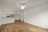 This efficiently designed single-story home offers a thoughtful layout across its one floor, combining comfort and functionality. Light wood laminate flooring runs consistently throughout the entire space, lending a clean, cohesive aesthetic to every room.

The combined kitchen and living area serves as the heart of the home. The kitchen is well-equipped with stainless steel appliances, including a full-size refrigerator and a range, set against crisp white cabinetry that extends to the ceiling for ample storage. Light granite-style countertops complement the white cabinetry, while a window fitted with vertical blinds allows natural light to fill the space. A ceiling fan overhead adds to the kitchen's functionality.

The living area is bright and open, featuring a textured ceiling, a ceiling fan with light fixture, a wall-mounted AC unit, and a window that frames a view of mature trees outside, bringing a sense of the outdoors in.

The spacious bedroom offers a generous footprint with a ceiling fan, a window with outdoor views, a wall-mounted AC unit, and a floor-to-ceiling mirrored sliding closet door that enhances the sense of space.

The bathroom features a granite-topped vanity with white cabinetry and chrome hardware, maintaining the consistent, clean design found throughout the home.