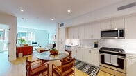 Located at 8809 Washington Blvd in the heart of Culver City, California, this modern single-floor residence combines clean architectural design with contemporary finishes to create a bright, functional living space. The open-concept layout connects the kitchen, dining, and living areas seamlessly, encouraging an easy flow throughout the home. The kitchen is well-appointed with floor-to-ceiling white shaker cabinetry, stainless steel appliances including a gas range, built-in microwave, and dishwasher, complemented by white subway tile backsplash and light wood flooring. A glass-top dining table sits adjacent to the kitchen, creating an inviting space for meals. The living area features large floor-to-ceiling windows that flood the space with natural light and provide direct access to a private balcony with outdoor seating. The bedroom is generously sized with plush carpeting, its own balcony access, and serene views of the surrounding neighborhood. Two bathrooms serve the residence — one featuring a glass-enclosed walk-in shower alongside a soaking tub, and the other a full tub-shower combination — both finished with neutral tile and clean, modern fixtures. Recessed lighting and crisp white walls throughout contribute to the home's bright, contemporary ambiance.