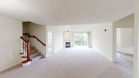 Located at 1165 Club Cir in Brookfield, Wisconsin, this two-story residence offers three bedrooms and three bathrooms across a generously proportioned layout spread over two floors. The main level forms the heart of the home, where a combined kitchen and living area provides an open, functional space for everyday living. The kitchen features warm, rich-toned cabinetry, white countertops, and black Whirlpool appliances including a range, dishwasher, and over-the-range microwave, all set above light hardwood-style flooring. The living room is highlighted by a tile-surround fireplace with a built-in niche above, adding a cozy focal point to the carpeted space. A standout feature of the upper level is the expansive primary bedroom, which boasts soaring vaulted ceilings, a sliding glass door opening to a private balcony with lush, wooded views, and a walk-in closet with wire shelving. The en-suite bathroom includes a walk-in shower with glass doors, a white vanity, and tile flooring. Additional bathrooms are well-appointed with tub-shower combinations, tile floors, and white cabinetry. The secondary bedrooms are carpeted and filled with natural light from large windows overlooking the surrounding greenery. A dedicated closet and hallway complete the thoughtful layout of this comfortable Brookfield home.