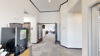 Located at 1882 Fox Rd in Rapid City, South Dakota, this well-appointed single-floor community amenity space offers a generous and thoughtfully designed layout across a wide footprint. The interior is characterized by soaring ceilings, neutral-toned carpet tile flooring, and crisp white walls accented by dark wood trim, creating a clean and modern aesthetic throughout.

The space is anchored by a grand lounge area featuring soaring ceilings, large windows that allow abundant natural light, and stylish barrel chairs arranged around a central table — ideal for gathering or relaxing. Adjacent to the lounge is a fully equipped kitchen showcasing dark cabinetry, striking marble-look quartz countertops, stainless steel appliances, and a large island with bar seating, perfect for community events or casual dining.

The fitness facilities are divided into two distinct areas: one dedicated to cardio equipment including multiple treadmills and ellipticals with wall-mounted TVs, and another outfitted with strength training equipment, free weights, a cable machine, and medicine balls — both rooms well-lit by recessed panel lighting.

A cozy media room features plush leather reclining chairs, movie-themed wall art, and a dedicated refreshment counter with a popcorn machine. Wide, carpeted corridors connect all areas, with glass-paneled doors and a welcoming entrance that sets an inviting tone throughout.