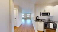 Located on Broad Street in Boston's historic Financial District, this one-bedroom, one-bathroom residence offers a well-designed layout across a single floor. Warm hardwood flooring runs throughout the unit, lending a cohesive and inviting feel to every room.

The kitchen is thoughtfully appointed with white shaker-style cabinetry, dark countertops, a classic white subway tile backsplash, and a full suite of stainless steel appliances including a range, microwave, dishwasher, and refrigerator. The space transitions naturally into an open corridor leading to the living area.

The living room is bright and airy, benefiting from multiple large windows that frame views of Boston's iconic surrounding architecture. The bedroom is generously proportioned, featuring a reach-in closet and large windows that allow ample natural light and city views.

The bathroom is clean and modern, with white tile surrounds in the tub/shower, a dark-countered vanity with white cabinetry, a medicine cabinet mirror, and neutral floor tiles.

Throughout the unit, the design aesthetic is clean and contemporary, with a neutral color palette, recessed lighting, and modern finishes that create a polished, move-in-ready environment in the heart of downtown Boston.